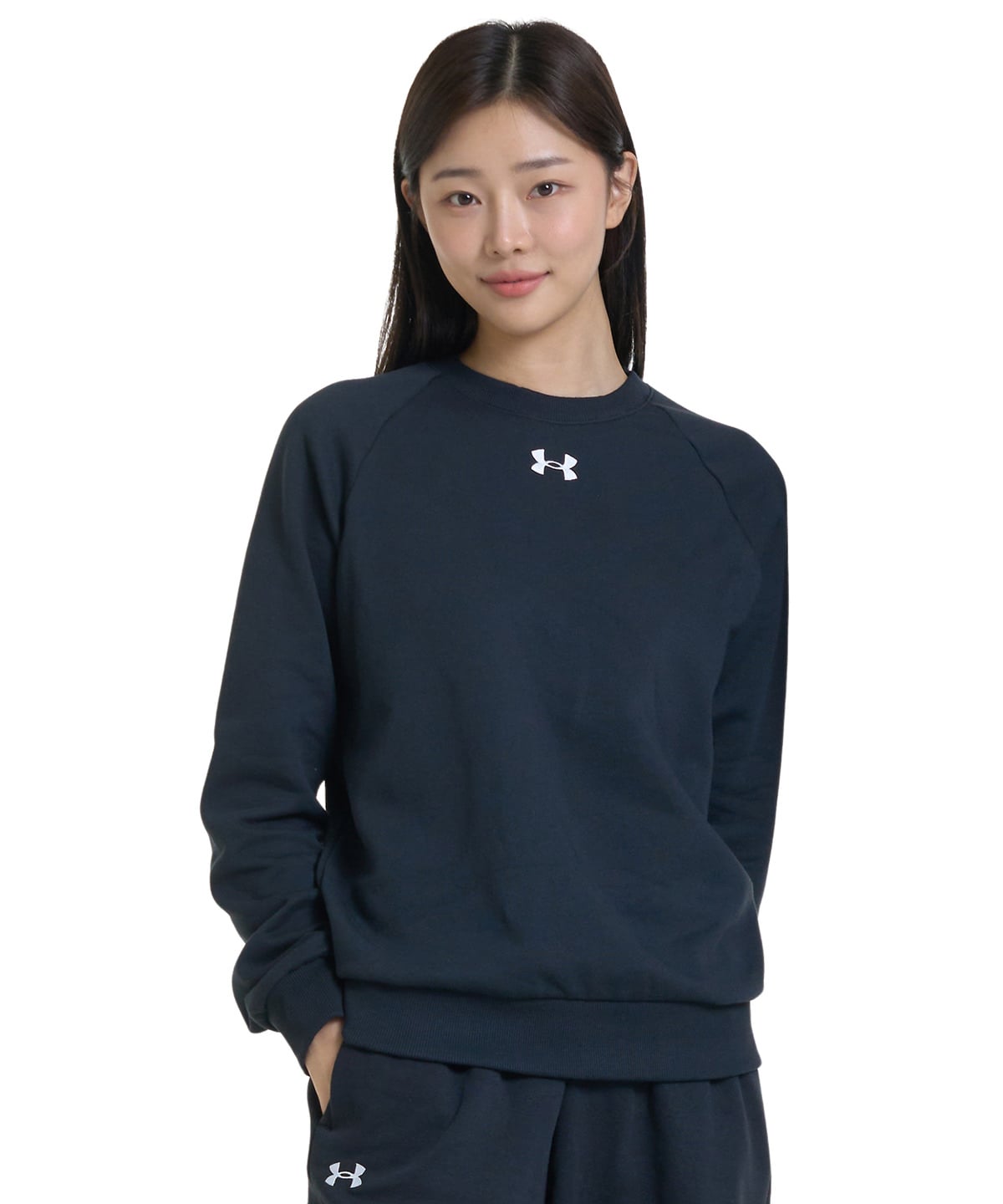 A woman modeling a dark navy Under Armour crewneck sweatshirt and matching sweatpants against a plain white background.